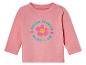 Un t-shirt rose à manches longues pour bébé avec le texte 'Hello World Here I Am' et une fleur souriante.
