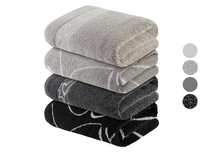 Pile de serviettes de bain grises et noires avec un motif de coeurs blancs