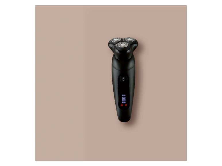 Rasoir électrique noir avec affichage numérique de la batterie sur fond beige.