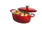 Cocotte ovale en fonte rouge avec couvercle, remplie de poulet rôti et de légumes.