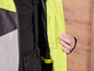 Un gros plan d'une veste jaune et noire avec une fermeture éclair et une poche