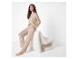 Femme en ensemble loungewear beige assise sur une chaise blanche texturée.
