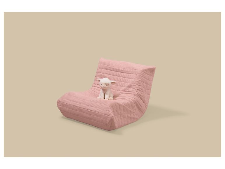 Fauteuil de sol rose avec une peluche d'agneau blanc assise dessus.