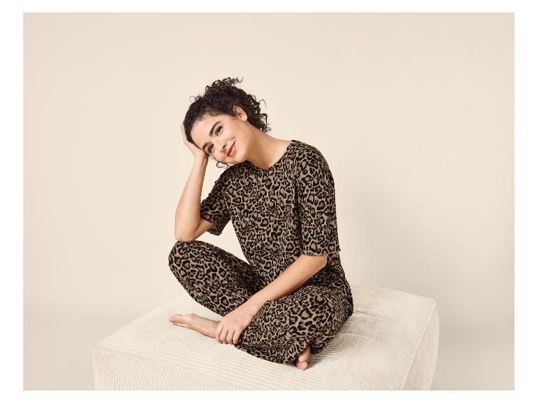 Femme en pyjama imprimé léopard assise sur un pouf et souriante