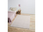 Un tapis rose clair dans une chambre avec un lit et une table de chevet.