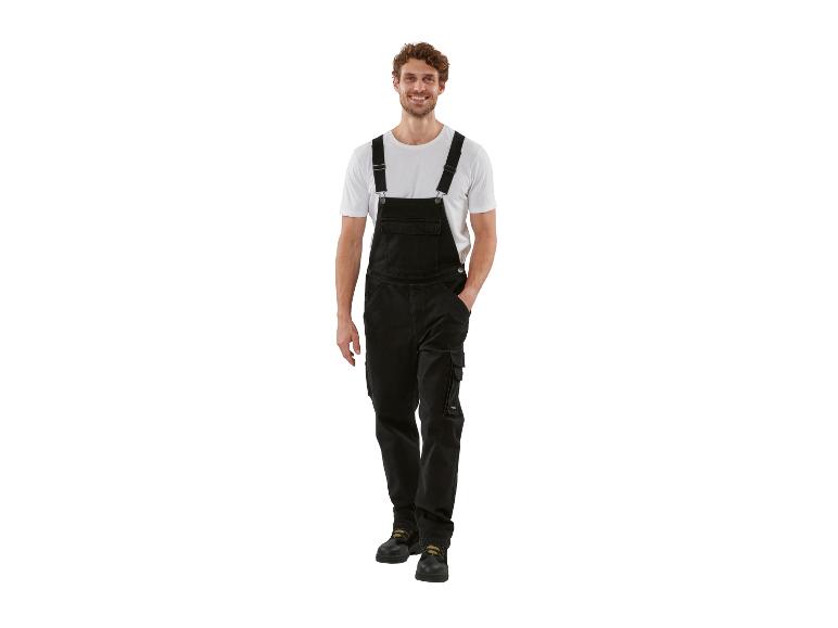 Homme souriant en salopette noire et t-shirt blanc.