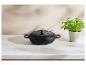 Cocotte en fonte noire sur un comptoir en marbre avec un pot de persil.