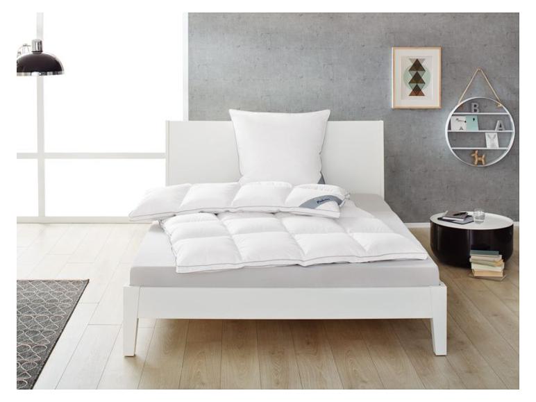 Lit avec literie blanche et couette dans une chambre moderne.