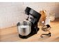 Robot pâtissier noir avec de la crème fouettée dans le bol, prêt à pâtisser sur un comptoir en bois.