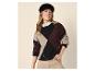 Femme souriante portant un pull argyle, une chemise blanche et un béret noir.