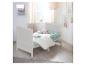 Lit bébé en bois blanc avec literie vert menthe et oreillers en forme d'étoile dans une pièce lumineuse.