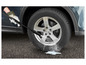 Une personne nettoie une roue de voiture avec un nettoyeur haute pression.