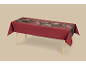Nappe rouge avec motif floral et de baies festif, drapée sur une table en bois.