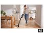 Une femme passe l'aspirateur sans fil SILVERCREST® sur un parquet. [image générée par l'IA]