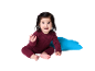 Bébé joyeux en ensemble tricoté bordeaux assis à côté d'un coussin bleu.