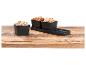 Pistaches, noix et bretzels dans des bols noirs sur une table en bois.