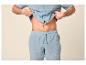 Homme en pyjama bleu clair, chemise et short, montrant son ventre.