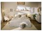 Chambre douillette avec lit beige, tapis et meubles en bois.