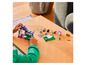 Un enfant construit une maison LEGO Minecraft avec des figurines.