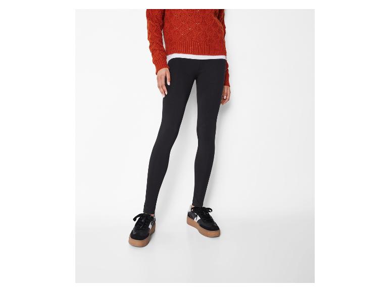 Legging noir femme avec un pull orange et des baskets noires.