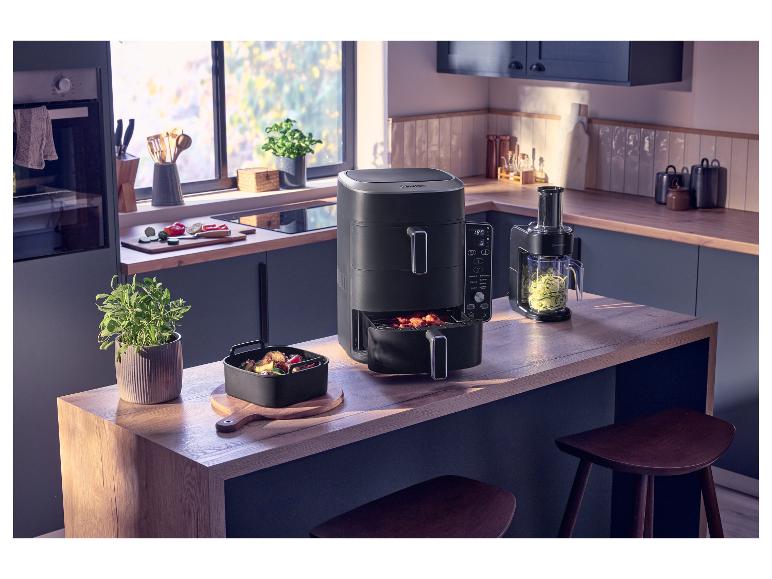 Comptoir de cuisine avec friteuse à air, coupe-légumes et légumes frais.