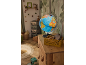 Globe terrestre lumineux sur une commode en bois dans une chambre d'enfant thème forêt.