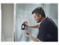 Un homme utilise un outil Bosch pour marquer une ouverture dans un mur.