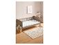 Un lit bébé avec une couette blanche et un tapis à pois.