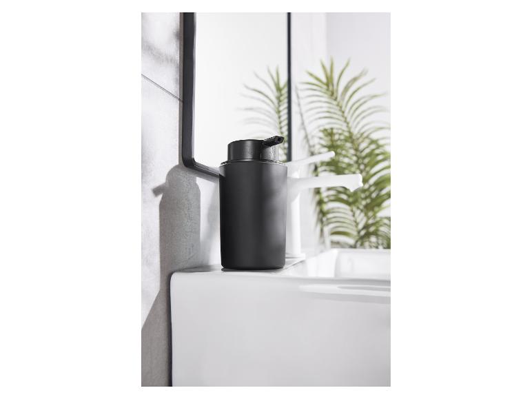 Un distributeur de savon noir élégant sur un lavabo blanc moderne.