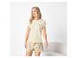 Femme en pyjama beige avec le texte 'Sea la vie' et un motif coquillage.