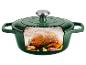 Marmite en fonte verte avec un poulet rôti, de l'ail et des herbes à l'intérieur, avec de la vapeur.