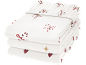 Pile de trois draps-housses blancs avec des motifs festifs de canne à sucre rouge, de nœud, de cœur et d'étoile.