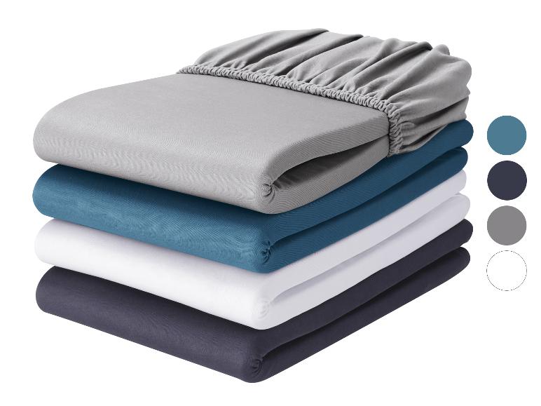 Pile de draps-housses gris, bleus, blancs et gris foncé, avec échantillons de couleurs.