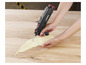 Une main utilise un outil sans fil Parkside pour travailler une feuille de bois.