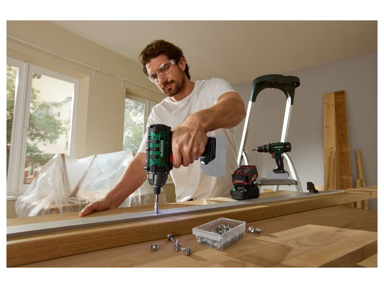 Un homme utilise une visseuse à chocs Parkside pour construire des meubles.