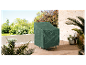 Une housse de mobilier vert foncé protège un fauteuil d'extérieur sur une terrasse en bois.