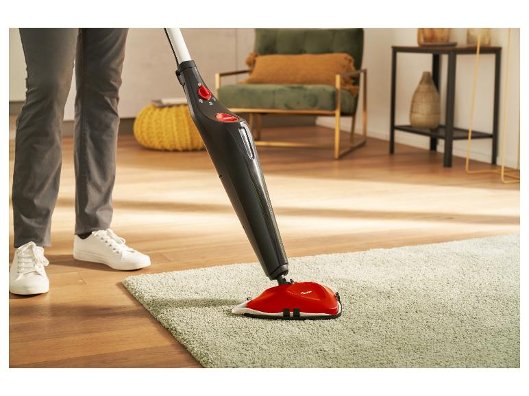 Personne nettoyant un tapis vert avec un balai vapeur Vileda dans un salon.