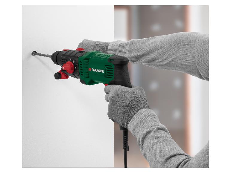 Perceuse à percussion Parkside verte et noire perçant un mur blanc.
