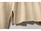 Détail de l'ourlet côtelé et de la fente latérale d'un pull en maille beige.