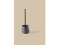 Brosse de toilettes moderne avec support en céramique gris foncé sur fond beige.