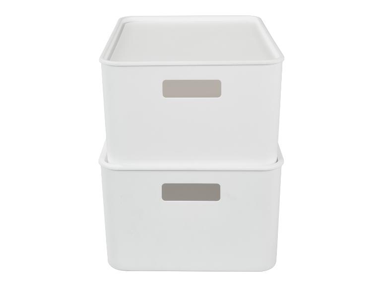 Deux boîtes de rangement blanches empilées avec couvercles et poignées découpées.