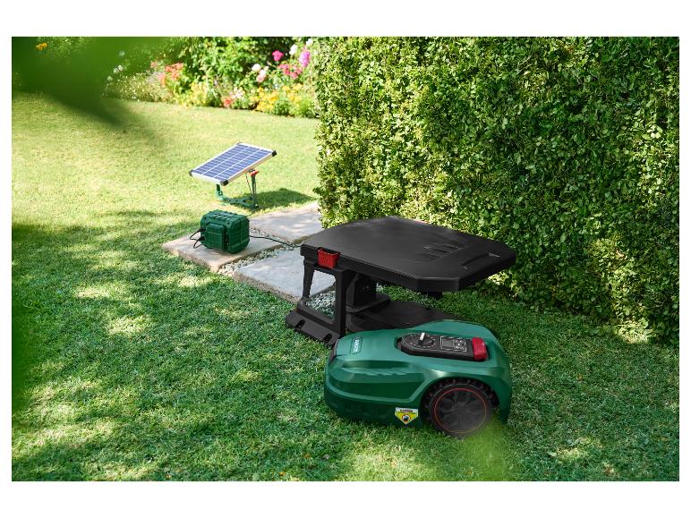 Robot tondeuse avec station de charge et panneau solaire dans un jardin.