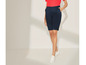 Une femme porte un pantalon bleu marine à taille haute et des baskets blanches.