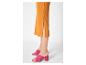 Jupe midi orange fendue sur le côté et mules à talons roses.