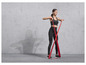 Une femme en tenue de sport fait des exercices avec un élastique de résistance rouge.