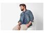 Un homme porte une chemise en jean et un pantalon beige.