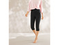 Une femme portant un legging noir capri et un haut rose.