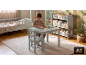 Garçon dessinant à une table d'enfant avec chaise dans une chambre avec lit et étagère à jouets.