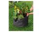 Un sac de plantation noir avec des poivrons et des herbes dans le jardin.