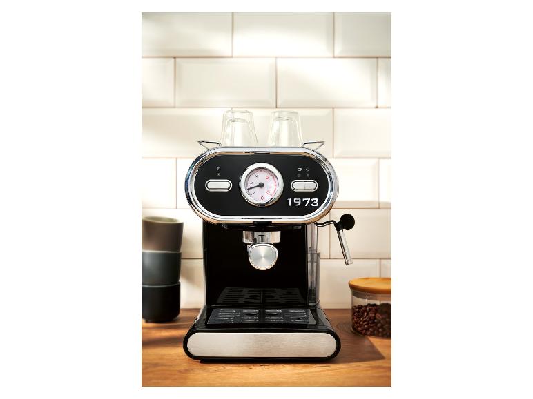 Machine à café noire devant un mur carrelé blanc sur un comptoir en bois